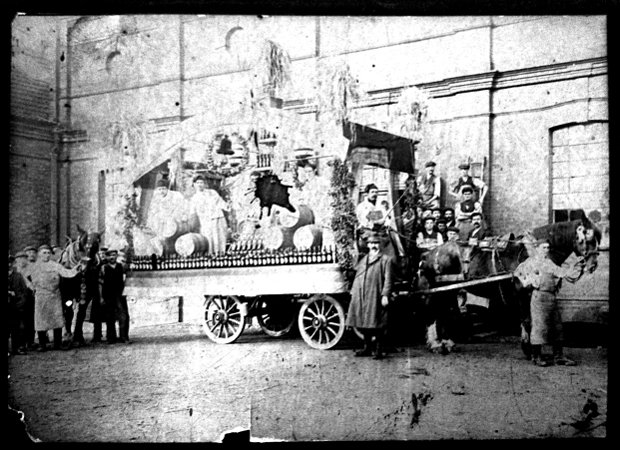 Brewery workers with beer barrels and hops on a carnival cart.