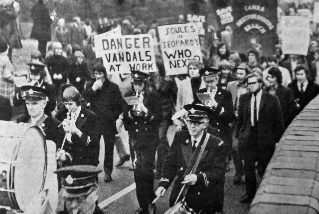 An old photo of people marching with a brass band.