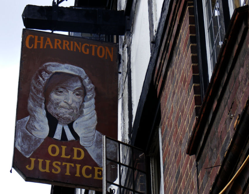 The sign for a London pub, The Old Justice, with a Charrington logo and the face of a judge in a long wig.