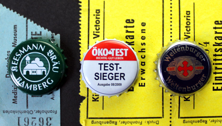 Three beer caps on old German ticket stubs.