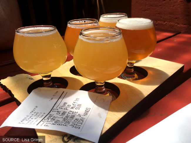 A taster flight of beers with tiny stem glasses and receipt.