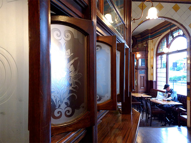 A view along the bar of a traditional Victorian pub with swivelling screens, with etched glass.