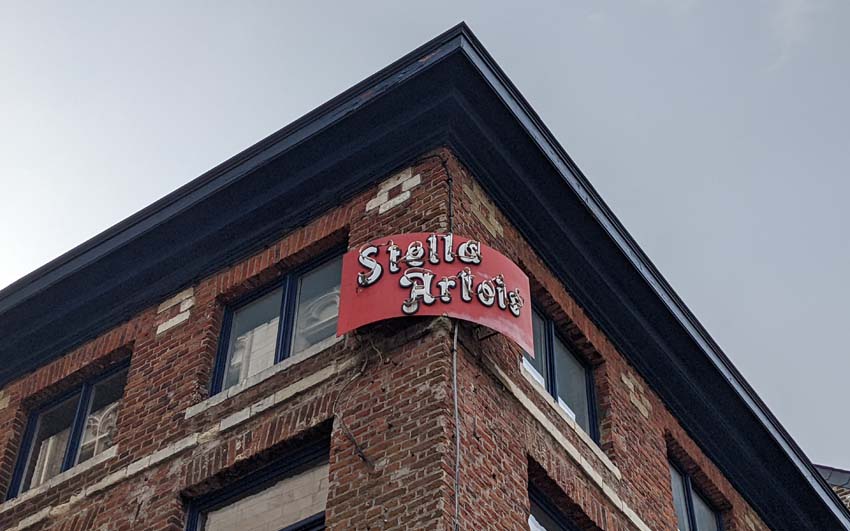 An old sign advertising Stella Artois on the corner of a bar in Leuven.