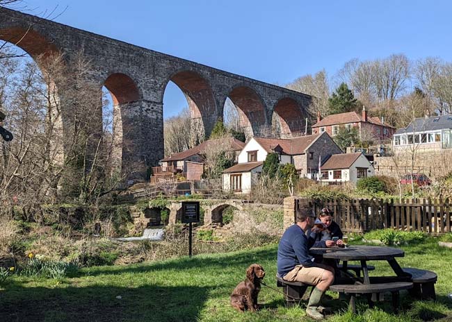 A beer garden with a viaduct in the background.