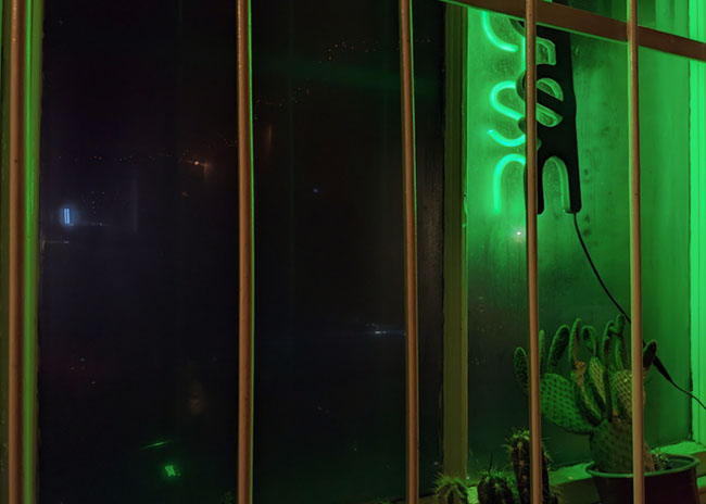 A green tinted window behind bars.