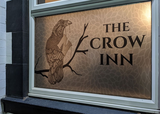 A frosted window with a crow and the name of the pub.