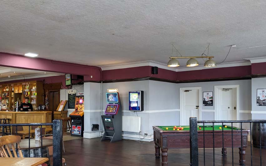 The interior of The Bulldog with light grey walls, pool table and fruit machine.