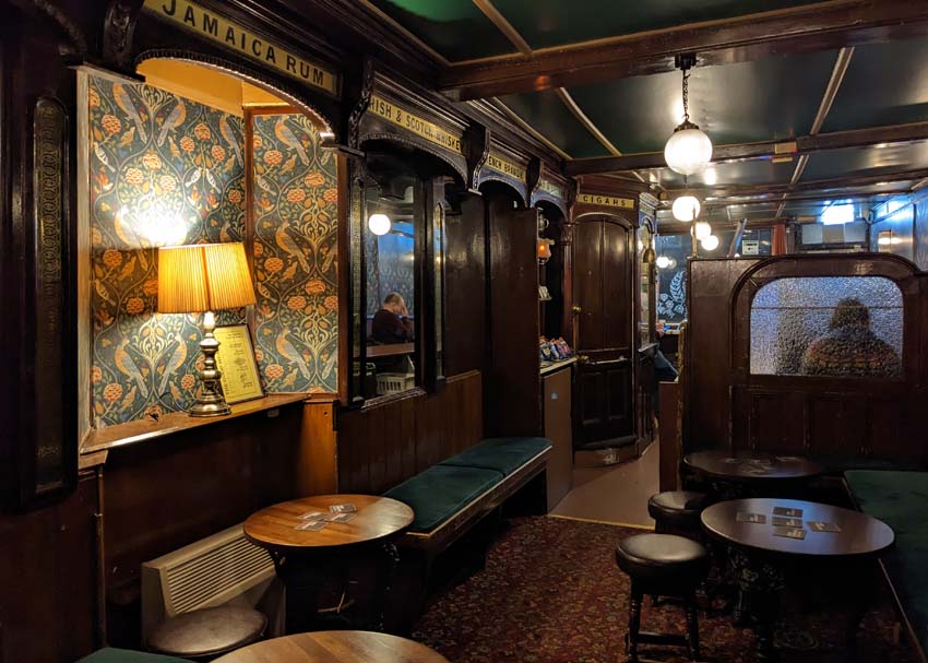 The historic interior of The Kings Head with wood panelling, old signage and cosy lighting.