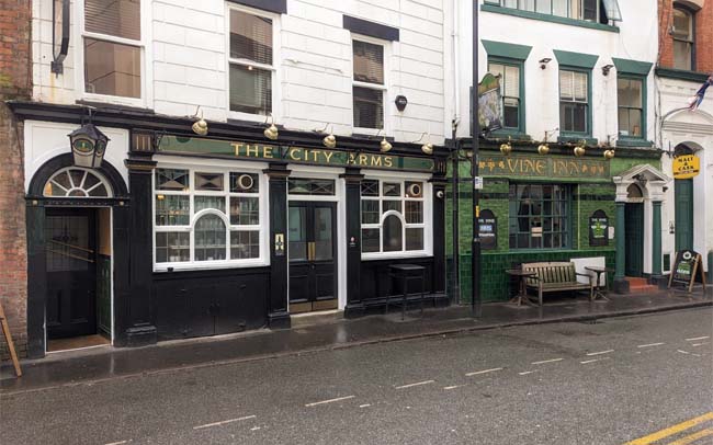 Two pubs side by side, The City Arms in black and the Vine Inn with green tiling.