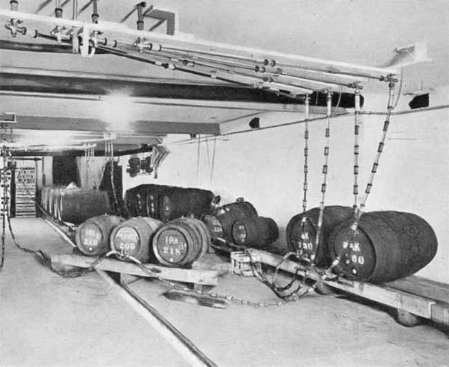 Several wooden casks on racks with a complicated system of pipes and tubes.