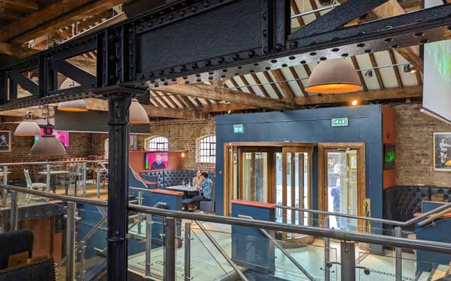 The interior of a modern pub with iron girders and leather seats.