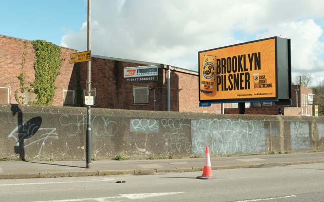 A billboard advertising Brooklyn Pilsner on an industrial estate.