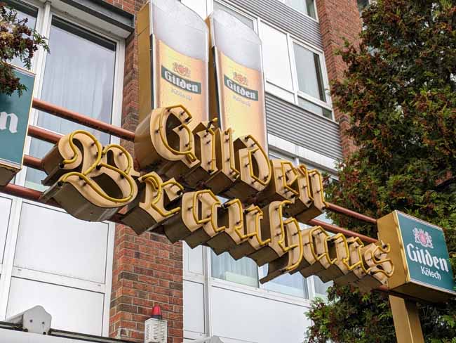 The huge neon sign for the Gilden Brauhaus on the front of a modern building.
