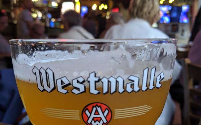 A glass of Westmalle Tripel in a busy Belgian bar.