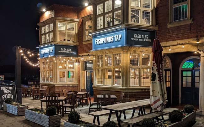 The exterior of a large pub at night. The sign reads 'Fishponds Tap'.