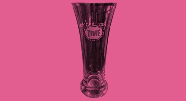 A fluted pilsner glass with the word 'Time' on one side and 'Smithwicks' on the other.